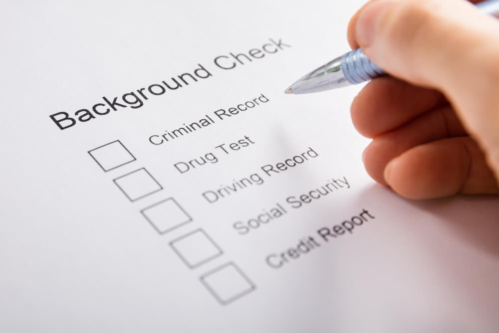 Close-up of Person Hand Filling Background Check Form